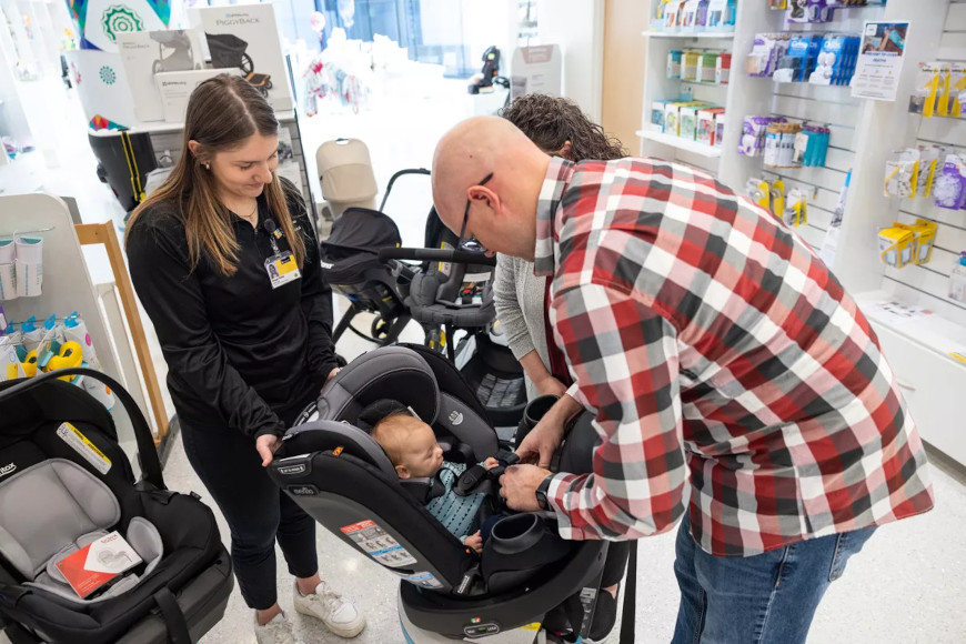 Safety Store staff helping parents check their baby's fit in a car seat